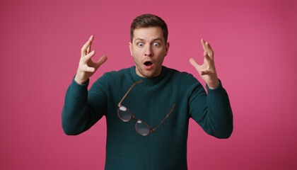 Fototapeta premium Astonishment in Color: A man with an open mouth and raised hands exhibits amazement against a vibrant pink backdrop. The image captures the emotion of shock and surprise in a moment.
