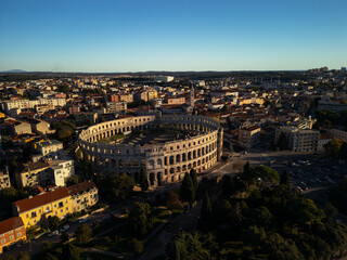 Fototapeta premium Epic aerial panorama of ancient Pula Arena at sunset. Cinematic historic Roman amphitheater and cityscape landscape in Pula, Croatia. High quality 12MP drone photography. 