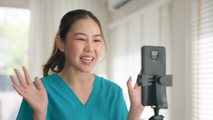 Young adult woman Gen Z asia people anti aging expert modern nurse live talk viral video selfie camera on mobile phone app mental health care. Online sharing digital virtual asian vlogger filming.