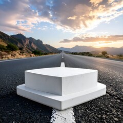 Concrete pedestal on road, leading to mountains under cloudy sunset sky