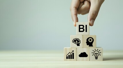 A hand placing a block with 'BI' on a stack of blocks with various business-related icons on a wooden surface