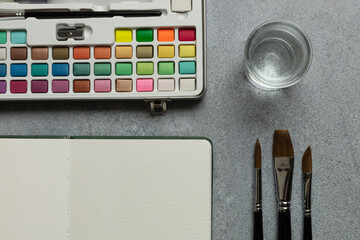 Blank Sketchbook and Watercolor Set on Gray Background
