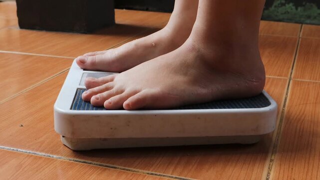 Close up of bare feet stepping onto a bathroom weighing scale on tiled floor at home, representing weight measurement, daily routine, personal health monitoring, and indoor lifestyle.