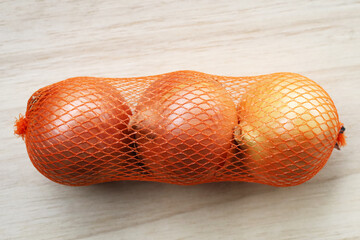 Fresh yellow onions packed in orange mesh bag