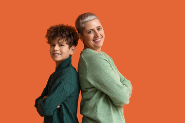 Teenage boy and his mother in green sweaters on orange background