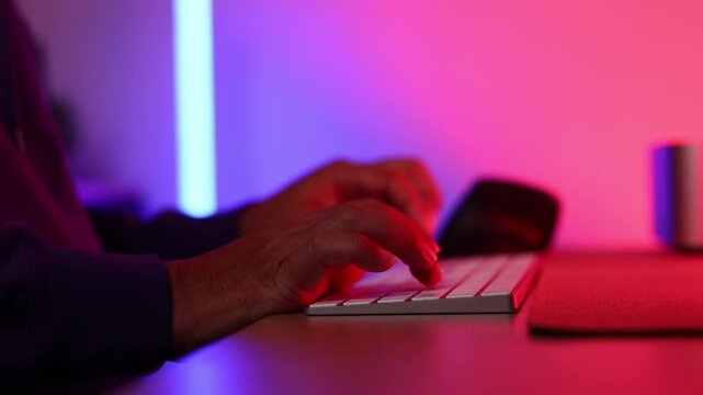 Closeup hand cyber crime. Senior man hacker hacking computer. anonymous hacker wearing black hoodie in dark room. online scam and cyber security threat.