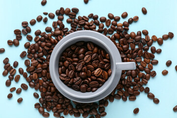 Cup with coffee beans on blue background