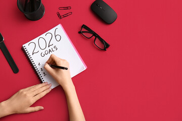 Woman with computer mouse writing goals on 2026 against red background