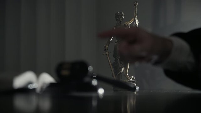 Judge points with finger and strikes a wooden gavel while the Statue of Justice stands in background under dramatic lighting. Courtroom authority, legal decisions.