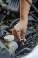 Close up of a  hand of woman pulling an engine oil dipstick to inspect oil level