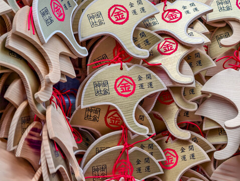 Kyoto, Japan. Closeup of ginkgo leaf shaped ema votive plaques hanging at Mikane Shrine, with wishes for wealth, money luck and good fortune.