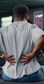 Man, fitness and back pain with discomfort in gym for workout accident, sprain or strain. Active, male person or sore spine with ache, injury or bad posture for overworked exercise or muscle tension
