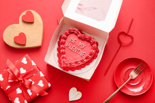 Opened box with sweet bento cake and hearts on red background. Valentine's Day celebration