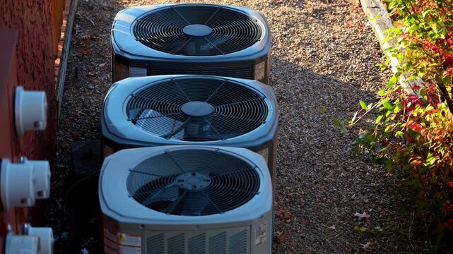 Home HVAC Air Conditioner system working outside the house. Bright autumn sunny day with beautiful foliage colors. Bushes leaves moving on the wind