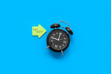 Alarm clock and sticky note with text RIGHT NOW on color background