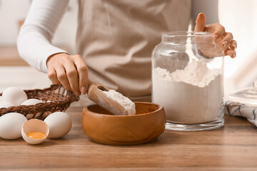 Woman preparing dough with ingredients on kitchen counter