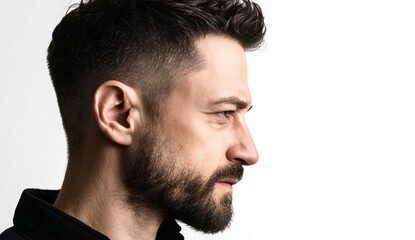 Obraz premium Side view of a man's face with a faded haircut showing textured dark brown hair and well-groomed beard against a plain white background