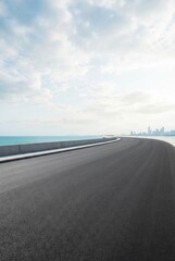 Fototapeta premium Empty coastal highway with panoramic ocean views and a cloudy sky.
