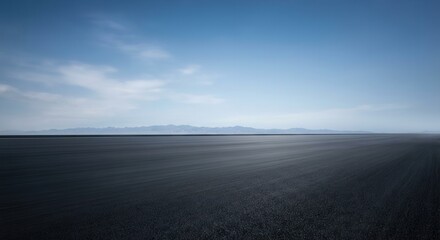 Vast open road under a clear blue sky with distant mountains.