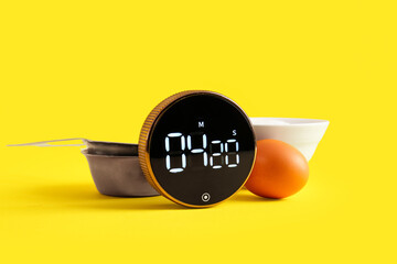 Modern kitchen timer, scoop, bowl and egg on yellow background