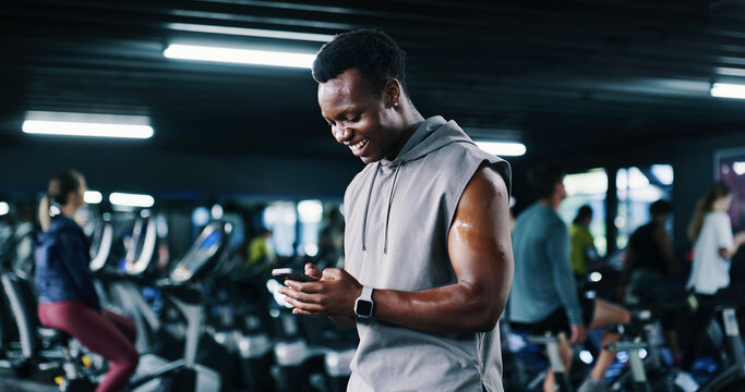 Fitness, man and happy with phone at gym for workout progress, membership renewal and sign up. People, athlete and smile with mobile app at night for exercise performance, training break and results