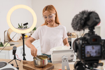 Female food blogger cooking pasta while recording video class in kitchen