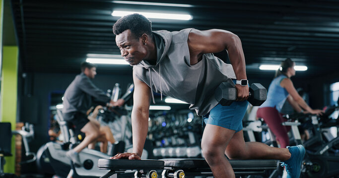 Fitness, weightlifting or black man in center with dumbbell, endurance or bicep training in bodybuilding. Exercise, active or athlete with equipment, intense workout or resilience in muscle gain.