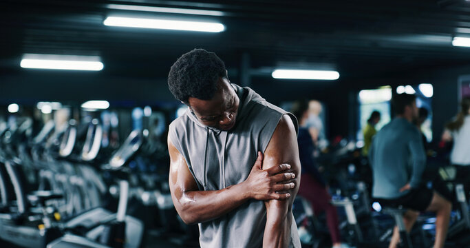 Man, fitness and arm pain with injury in gym for muscle tension, accident or emergency. Active, male person or sore bicep with ache or strain for joint inflammation or discomfort in health club