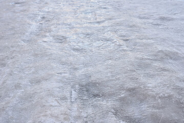 Fototapeta premium Road covered with ice in winter. Slippery ice on the road in winter. Frozen road dangerous for driving. Close-up. Selective focus.