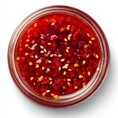 Spicy Chili Sauce with Red Peppers and Sesame Seeds in a Clear Glass Jar Isolated on White Background