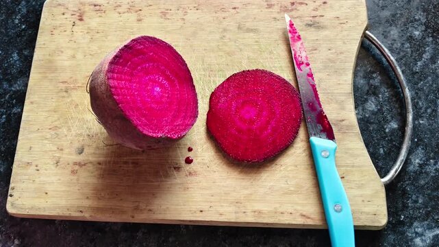 Freshly sliced red beetroot on a wooden cutting board with a kitchen knife