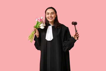 Portrait of young female judge with bouquet of flowers on pink background. International Women's Day