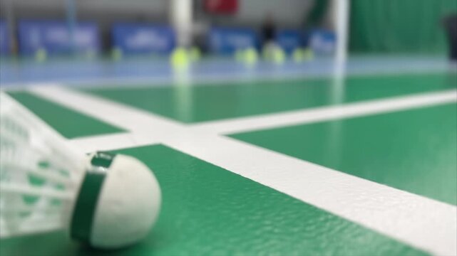 Close-up of a shuttlecock on a green badminton court line with shallow depth of field, highlighting texture and focus for training and game concepts