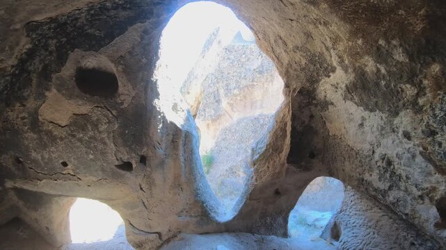 Fairy chimneys and ancient cave monasteries carved into volcanic rock landscapes of Cappadocia. Historic hoodoo formations reveal stone dwellings spires valleys seen from curious traveler view.