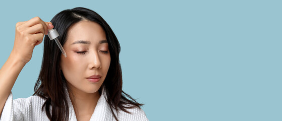 Young Asian woman with serum on blue background, closeup