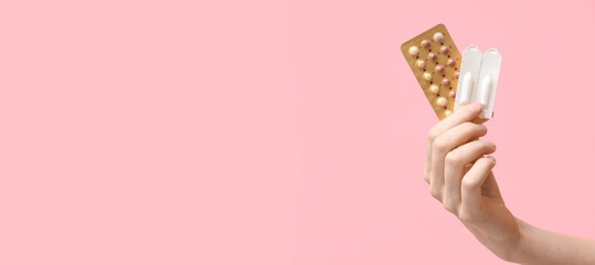 Female hand with birth control pills and vaginal suppositories on pink background with space for...