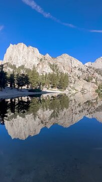 Mirror image of rocky mountains reflecting on the deep blue surface of Lone Pine Lake, Eastern Sierra, California