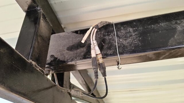 Close-up of CCTV camera BNC connectors and power cables installed on a black metal roof frame