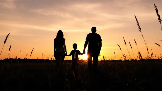 Family walking together at sunset in field. Silhouetted figures create warm, joyful atmosphere. Memorable moments captured in beautiful outdoor scene.