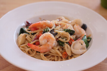 Spaghetti with shrimp and basil on wooden table, italian food