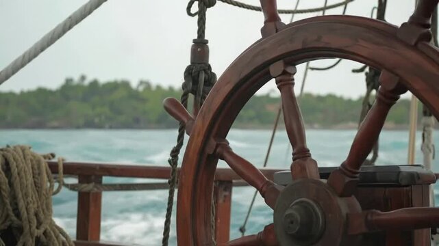 Close-up of ship's wooden helm as waves crash against the side in a stormy ocean
