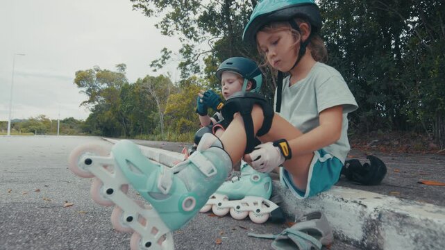 Kids put on roller skates sitting on the street and prepare themself to do their first attempts in the sport