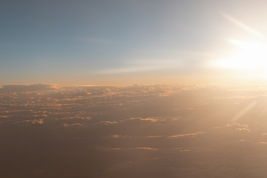 Sunrise above clouds with warm golden light in the sky