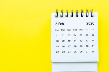 Top view of February 2026 table calendar with space for text on yellow background.