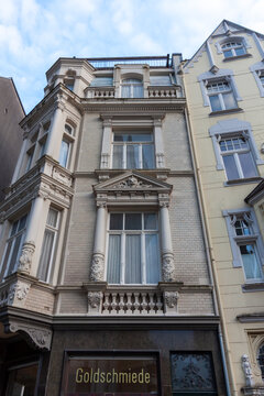 Detailed view of a tall, narrow historic building facade in Aachen, Germany. The architecture features decorative window frames, a gabled roof, and classical ornaments in the old town