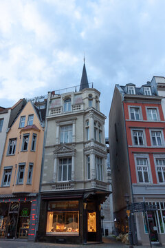 Full view of a historic neoclassical corner building in Aachen, Germany. The architecture features a multi-story bay window (erker) with decorative columns, a jewelry shop (Goldschmiede)