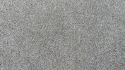 High-angle shot of a dark grey asphalt surface. The fine, grainy texture provides a uniform and neutral background, ideal for urban and industrial design themes, pattern and backgrounds. Zenith view. © Stefano Tammaro