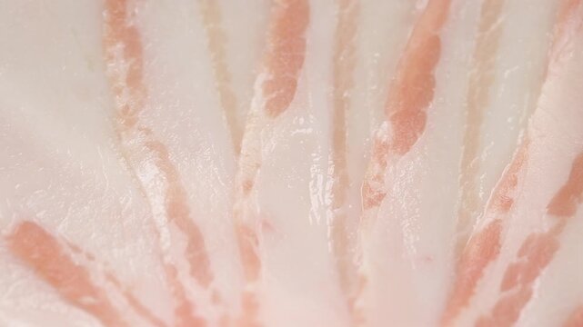 Texture of thin raw pork belly slices rotating. Close up view