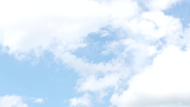 Fluffy white clouds drifting across a clear blue sky on a sunny summer day timelapse