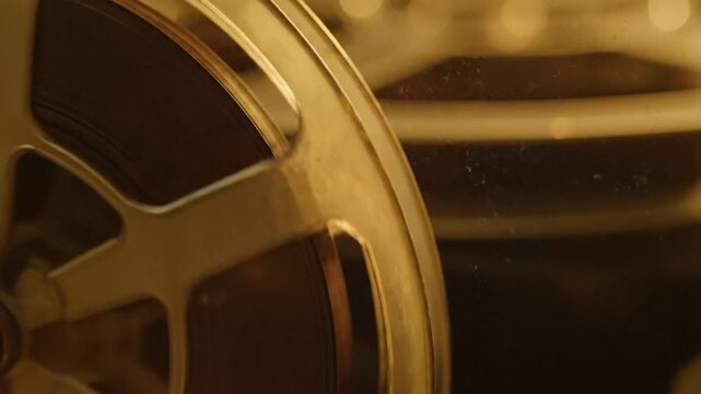 Close up view of old film reel playing showing celluloid film in motion during vintage movie projection